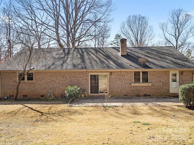 rear view of house featuring a patio, brick siding, a shingled roof, crawl space, and a chimney