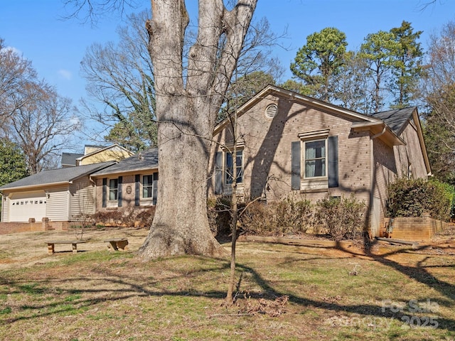 view of front of property with an attached garage, brick siding, and a front yard