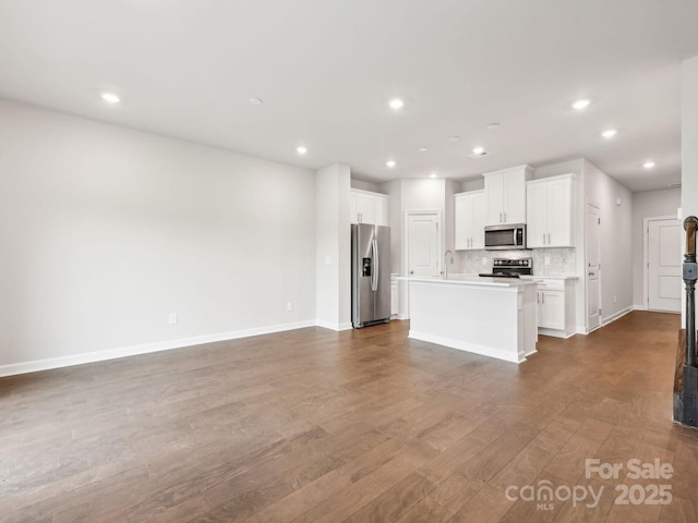 kitchen featuring stainless steel appliances, dark wood-type flooring, white cabinets, open floor plan, and tasteful backsplash