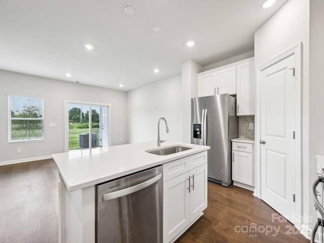 kitchen with a center island with sink, appliances with stainless steel finishes, dark wood-style flooring, a sink, and backsplash