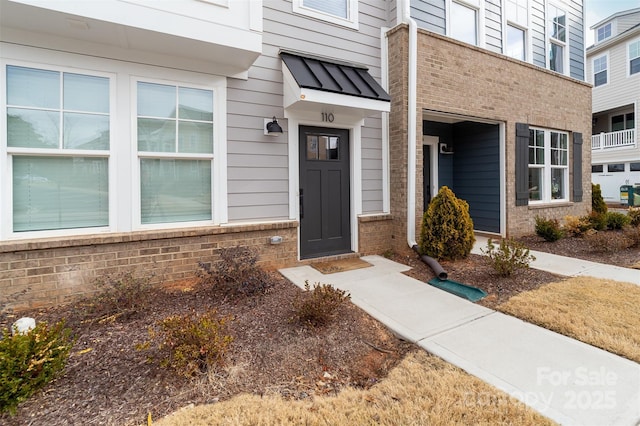 property entrance featuring a standing seam roof, metal roof, and brick siding