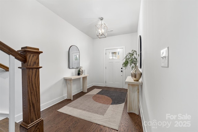 foyer with baseboards, wood finished floors, stairs, and an inviting chandelier