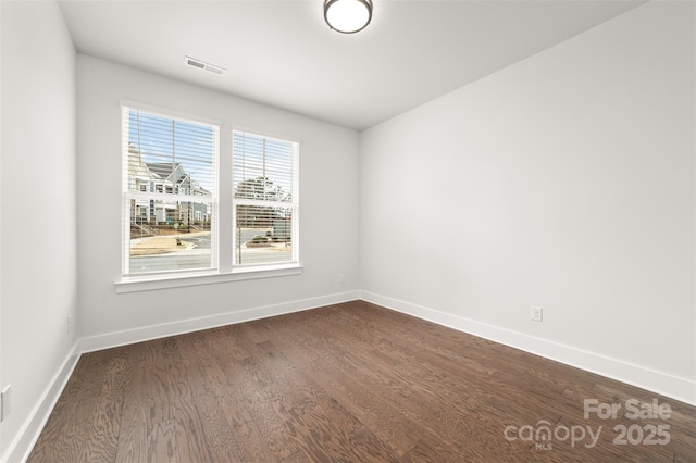 unfurnished room featuring baseboards, visible vents, and dark wood-type flooring