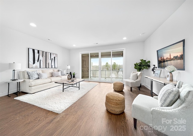 living area featuring baseboards, wood finished floors, and recessed lighting