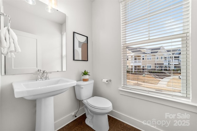 bathroom with toilet, a sink, baseboards, and wood finished floors