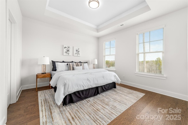 bedroom featuring dark wood-style floors, a tray ceiling, and visible vents