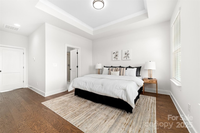 bedroom with dark wood finished floors, a raised ceiling, visible vents, and baseboards