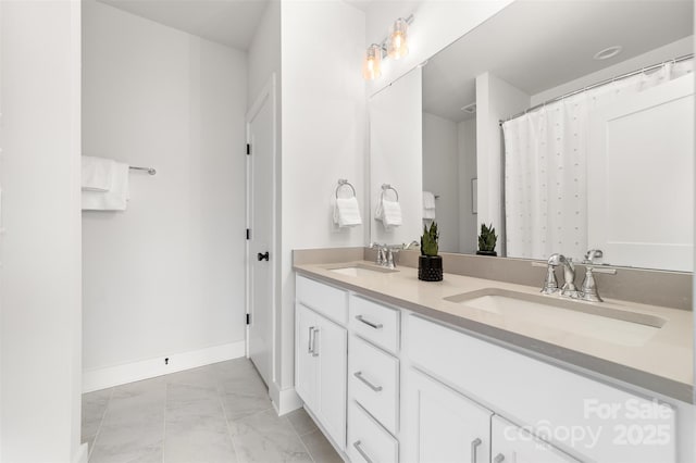 full bathroom with double vanity, marble finish floor, baseboards, and a sink