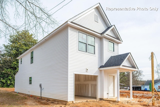 view of side of home with a garage and roof with shingles