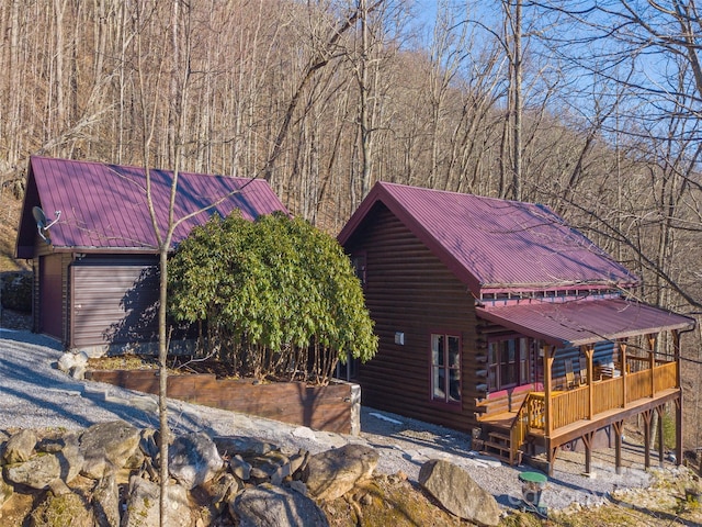 view of front facade featuring metal roof, log exterior, and a wooden deck