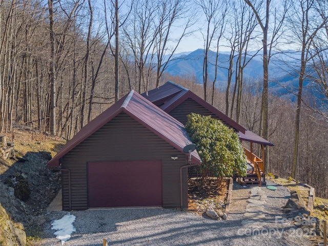 view of side of home with an outdoor structure, metal roof, a mountain view, and a detached garage