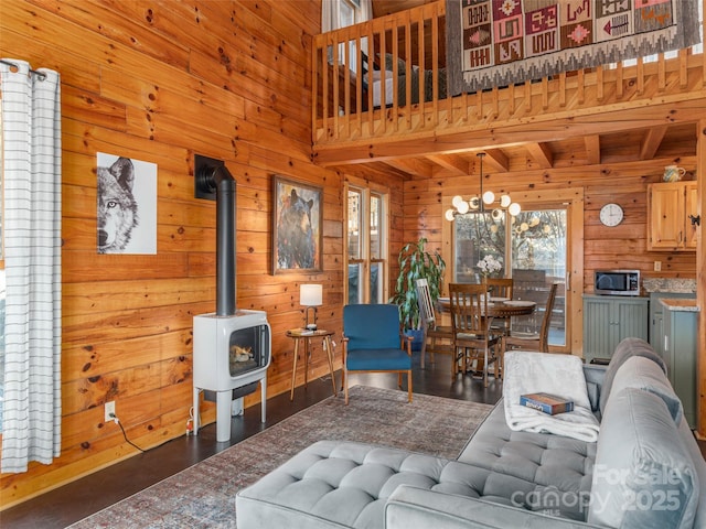 living area with a wood stove, a notable chandelier, wood walls, and a high ceiling