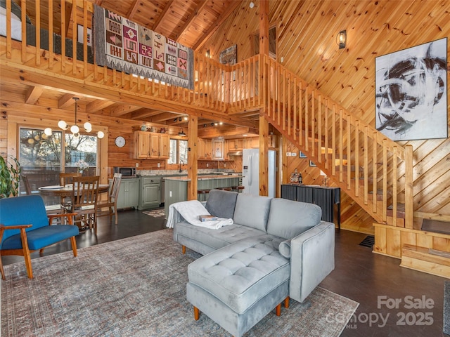 living area featuring wood ceiling, an inviting chandelier, stairs, and wooden walls