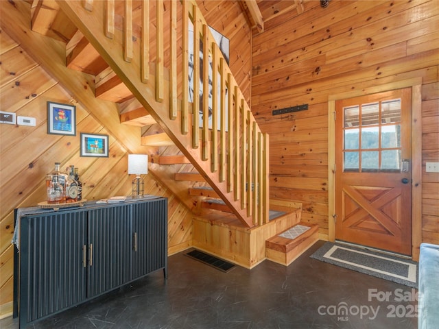 staircase featuring wood walls, visible vents, and beam ceiling