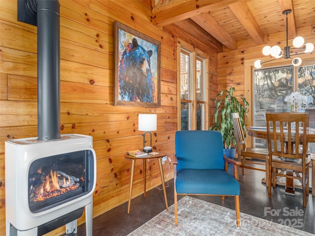 sitting room with wooden ceiling, beamed ceiling, a wood stove, wood walls, and a notable chandelier