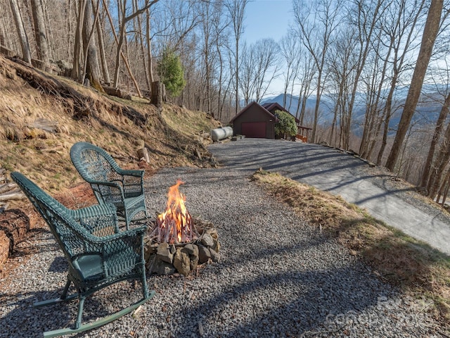 view of yard featuring a garage, an outdoor fire pit, and a mountain view