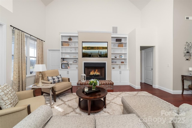 living area featuring high vaulted ceiling, wood finished floors, visible vents, baseboards, and a brick fireplace