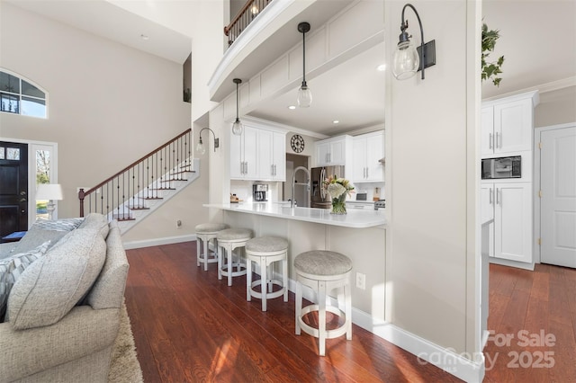 kitchen with stainless steel fridge, open floor plan, dark wood-type flooring, a kitchen bar, and black microwave