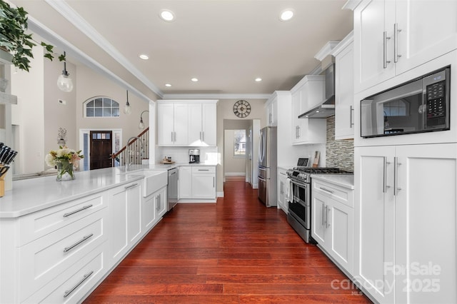 kitchen featuring stainless steel appliances, light countertops, and wall chimney range hood