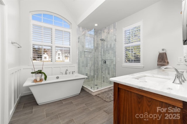 bathroom with wainscoting, a soaking tub, vanity, a shower stall, and wood finish floors