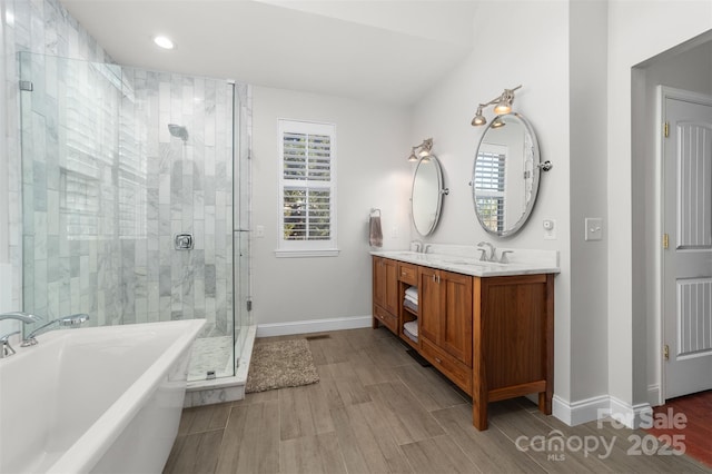 full bath featuring double vanity, a soaking tub, wood finish floors, a shower stall, and a sink