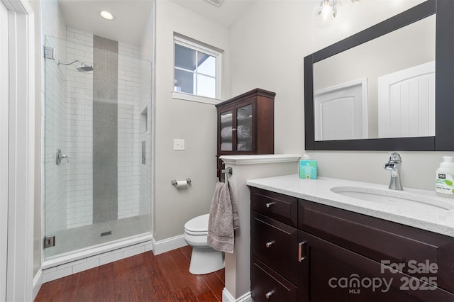 bathroom featuring a stall shower, vanity, toilet, and wood finished floors