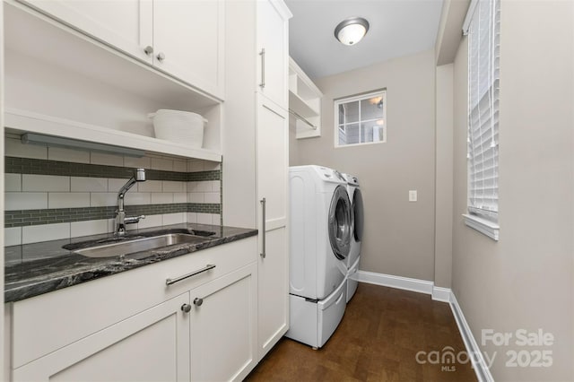 laundry room featuring cabinet space, baseboards, dark wood-type flooring, independent washer and dryer, and a sink