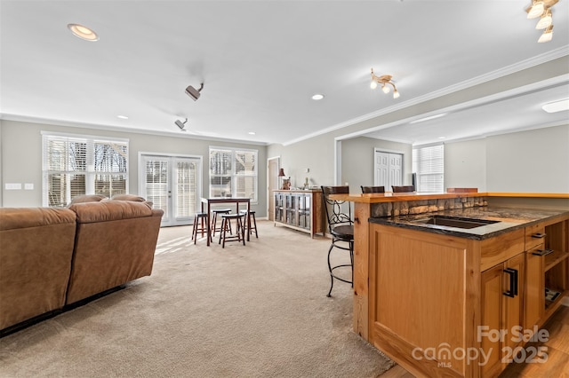 kitchen featuring open floor plan, french doors, a breakfast bar area, and ornamental molding