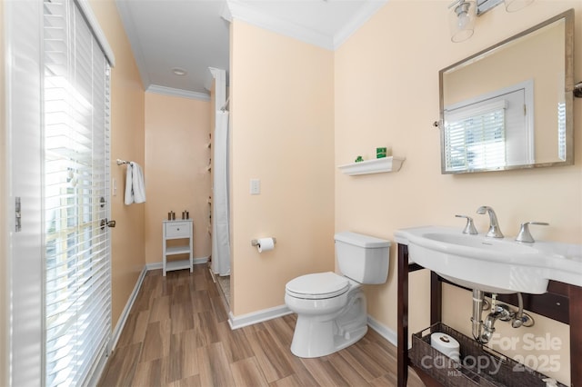 bathroom with baseboards, crown molding, toilet, and wood finished floors