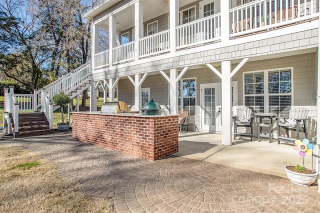 back of property with exterior kitchen, a patio area, and stairway