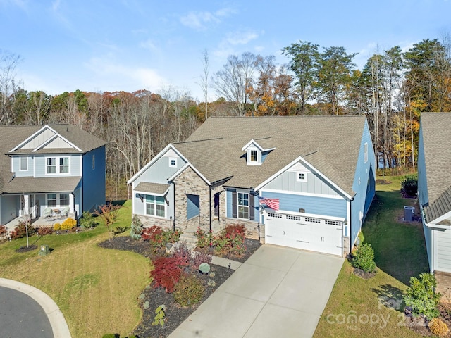 view of front of property featuring board and batten siding, a garage, stone siding, driveway, and a front lawn