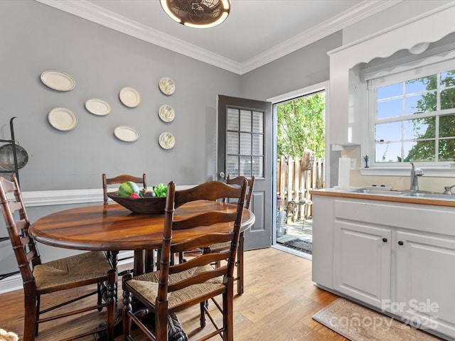 dining area with light wood-style floors and crown molding