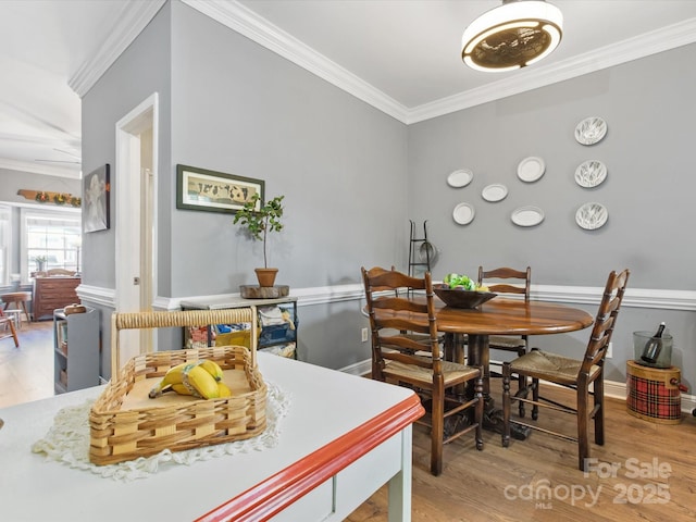 dining space with baseboards, ornamental molding, and wood finished floors