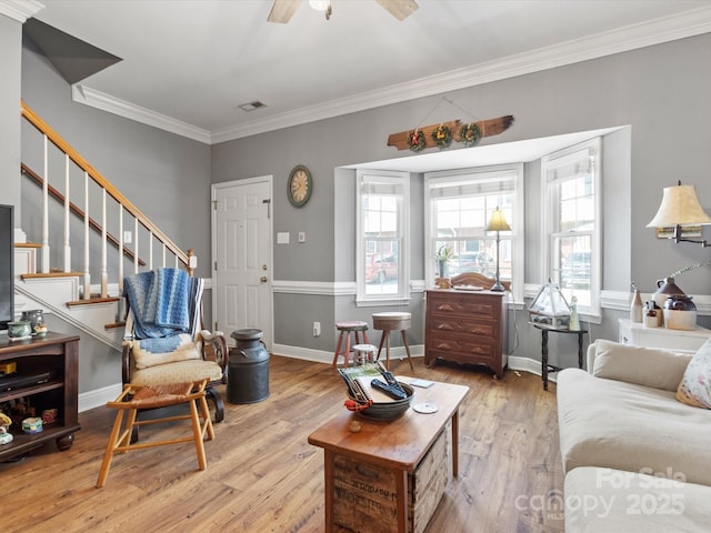 living room with stairway, visible vents, wood finished floors, and ornamental molding