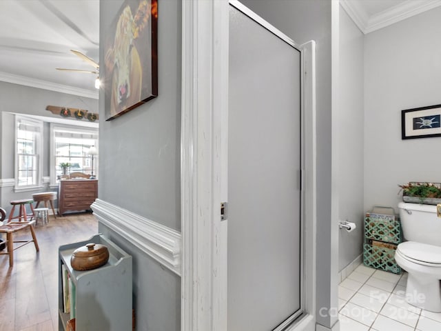 full bath featuring tile patterned flooring, toilet, baseboards, a stall shower, and crown molding