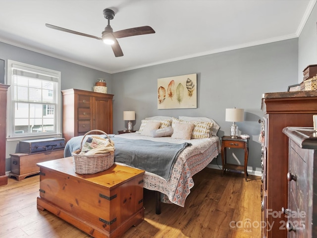 bedroom featuring ceiling fan, crown molding, baseboards, and wood finished floors