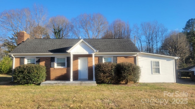 view of front of property with brick siding, a chimney, a front yard, and a shingled roof