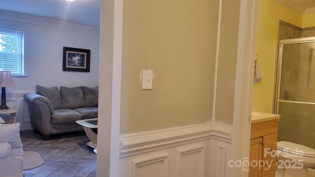 interior space with ornamental molding, wainscoting, and a decorative wall