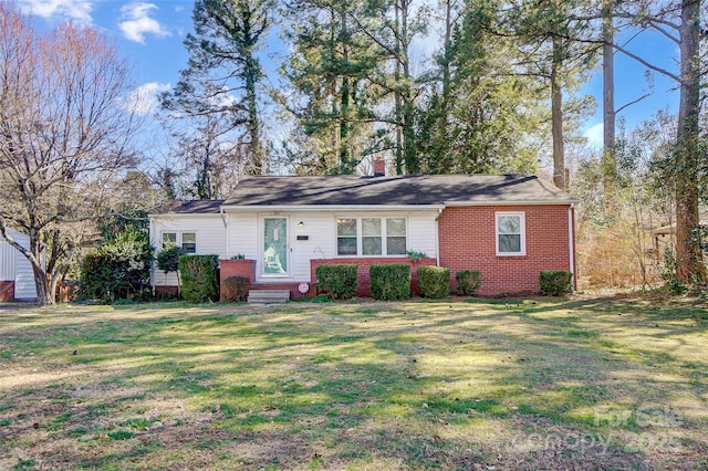 ranch-style home with brick siding, a front lawn, and a chimney