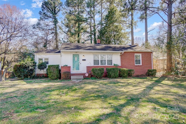 view of front of home with a chimney, a front lawn, and brick siding