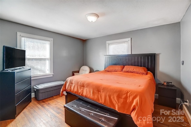 bedroom featuring multiple windows, light wood-type flooring, and baseboards