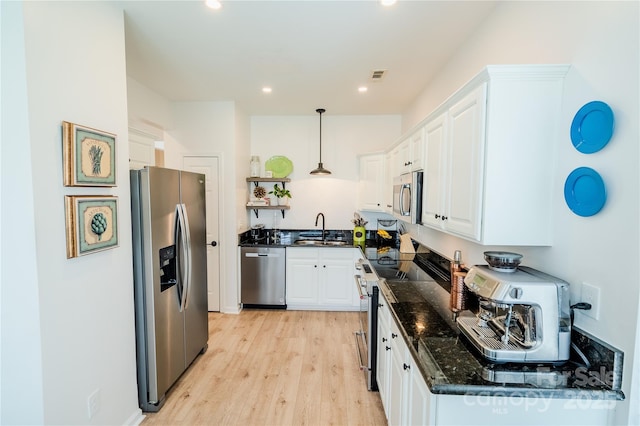 kitchen featuring dark stone countertops, visible vents, white cabinets, appliances with stainless steel finishes, and light wood finished floors