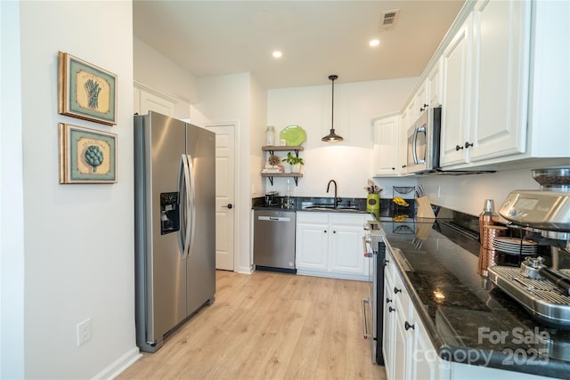 kitchen with a sink, white cabinets, light wood-style floors, and stainless steel appliances