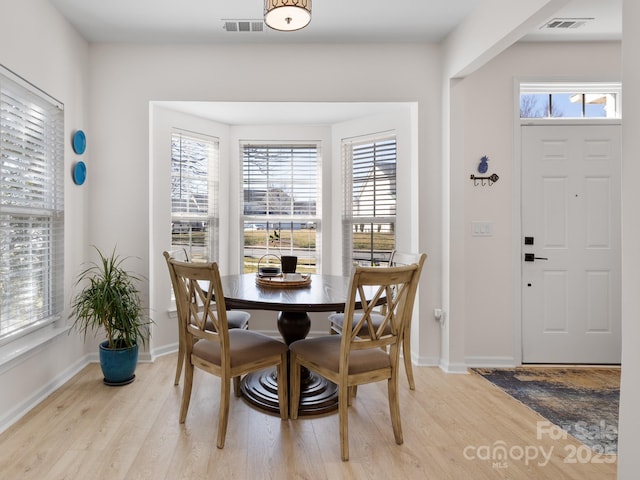 dining area featuring light wood finished floors, visible vents, and a wealth of natural light