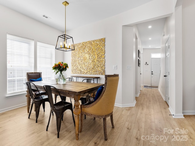 dining space featuring visible vents, baseboards, a notable chandelier, and light wood-style floors