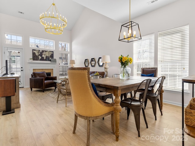 dining area featuring light wood-type flooring, a notable chandelier, and a healthy amount of sunlight