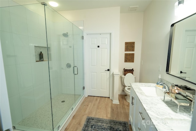 bathroom featuring a shower stall, vanity, visible vents, toilet, and wood finished floors