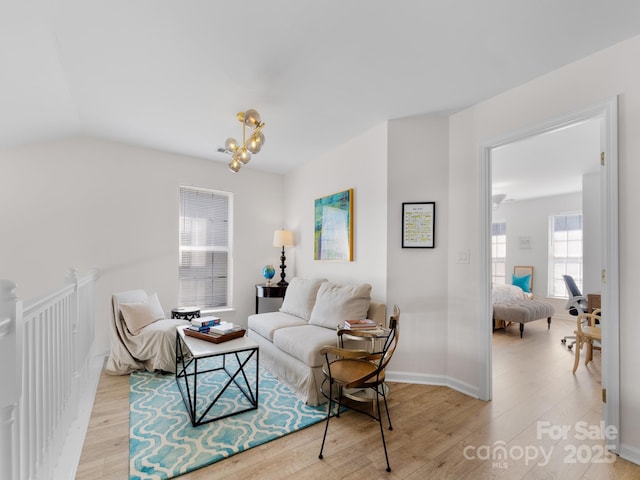living area with an inviting chandelier, light wood-style floors, and lofted ceiling