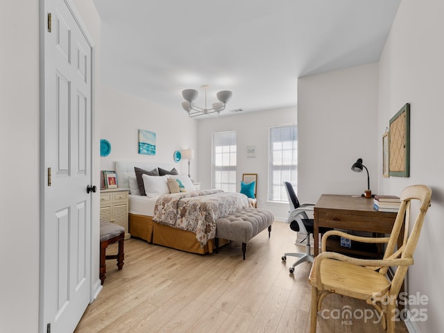 bedroom with visible vents, light wood-style flooring, and a notable chandelier
