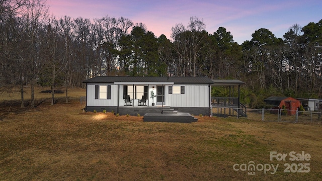 view of front of property with metal roof, a porch, fence, crawl space, and a lawn